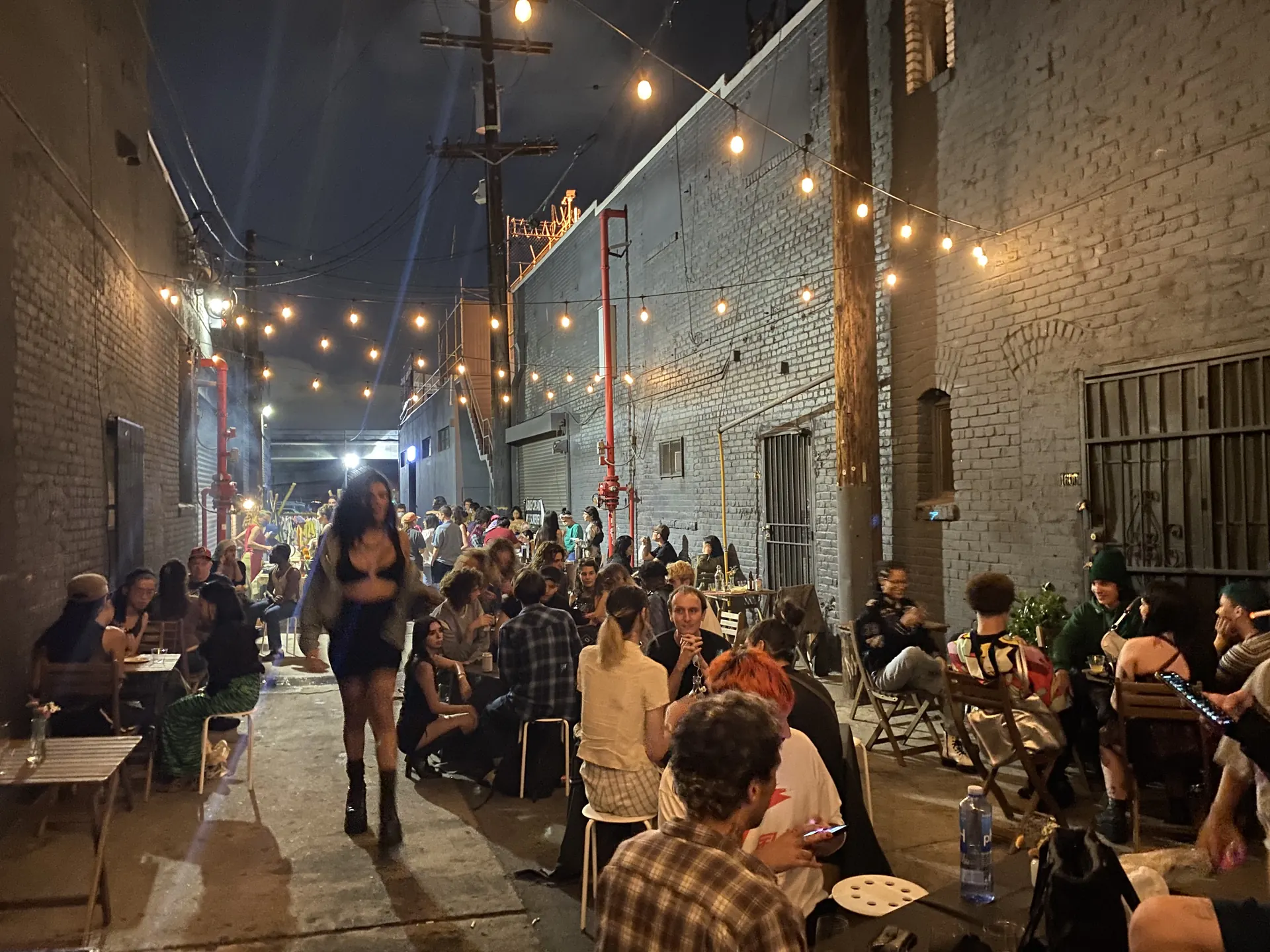 The alley at night, full of guests at tables under string lights