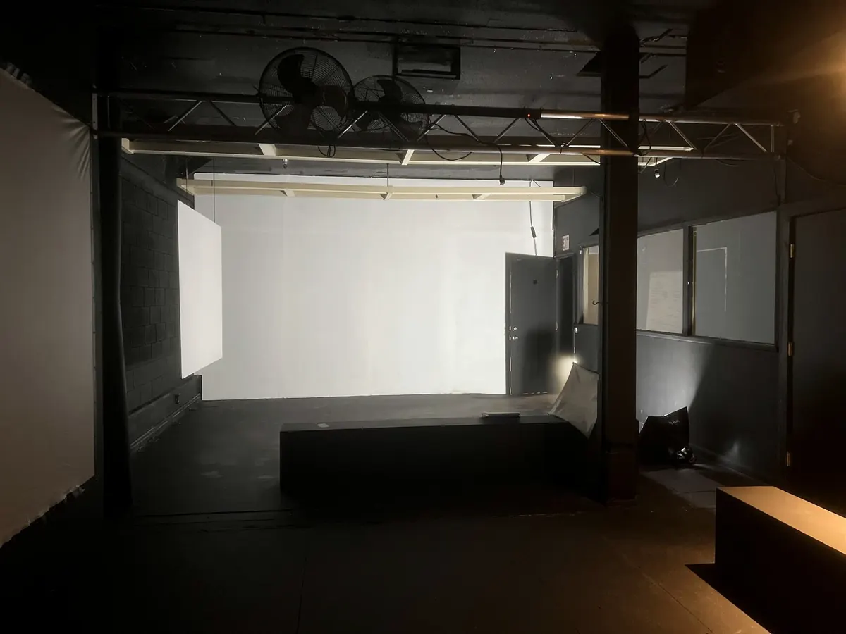 Studio B empty: a dark room with a lighting grid and a white wall