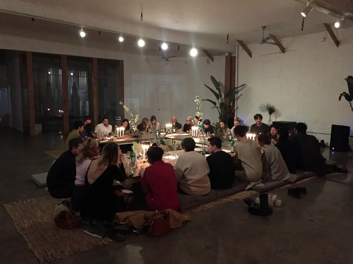 Studio A in the evening, guests seated on the floor around a long candlelit table