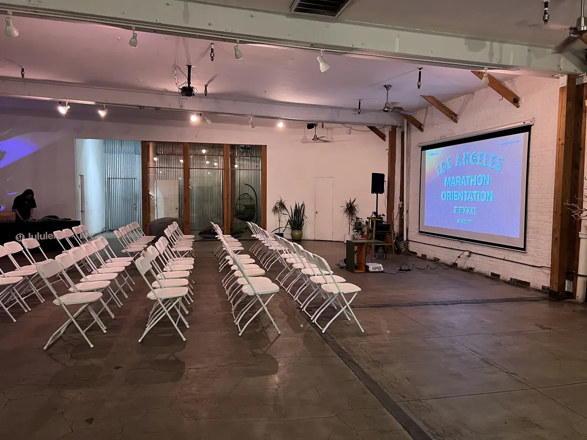 Rows of white chairs facing a projector screen in the Loft, in daylight