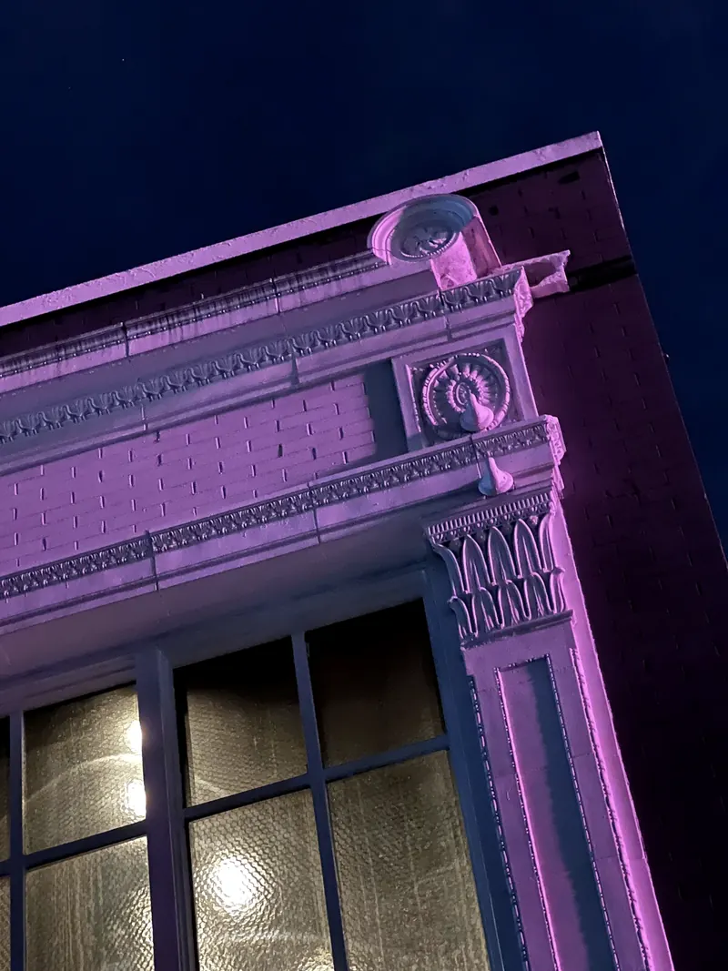 A corner of the building at night, washed in pink light