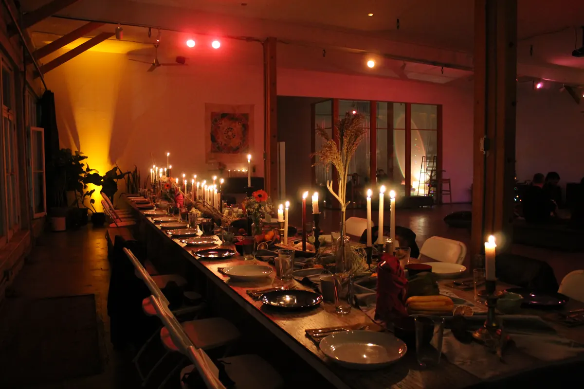 A long candlelit table in the Loft, with warm colored light on the walls
