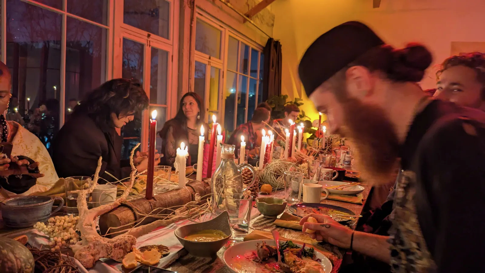 Guests at a long candlelit table beside the Loft windows