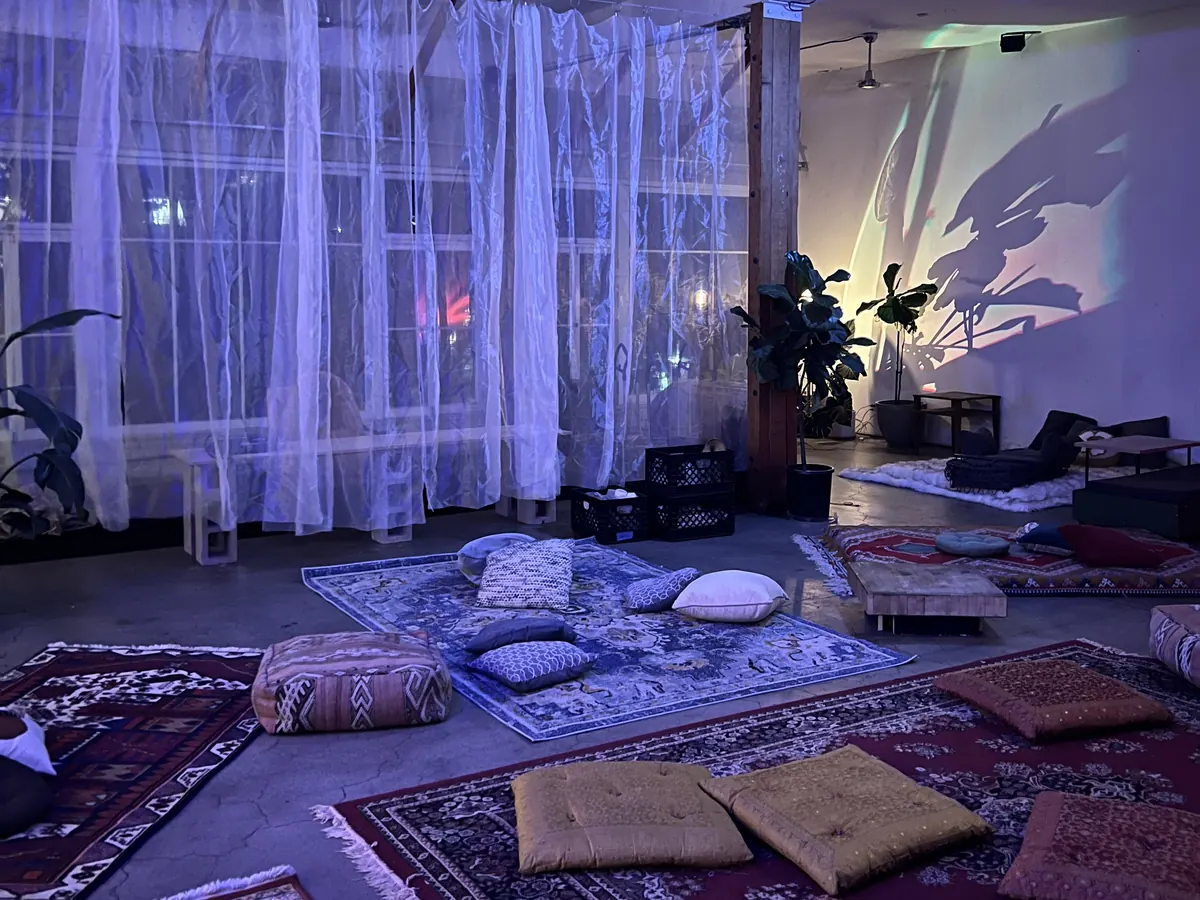 Rugs and floor cushions laid out in the Loft, with sheer curtains over the windows